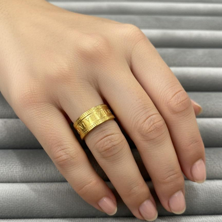 Gold ring on a hand against a gray background