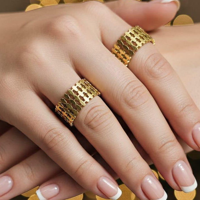 Close-up of a hand wearing gold rings with a blurred bokeh background