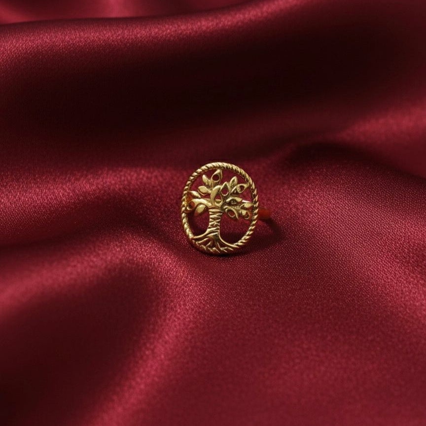 Gold ring with a tree design on a red satin background