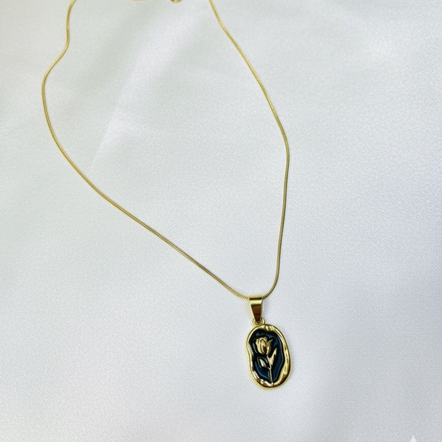 Gold necklace with a black pendant on a white background