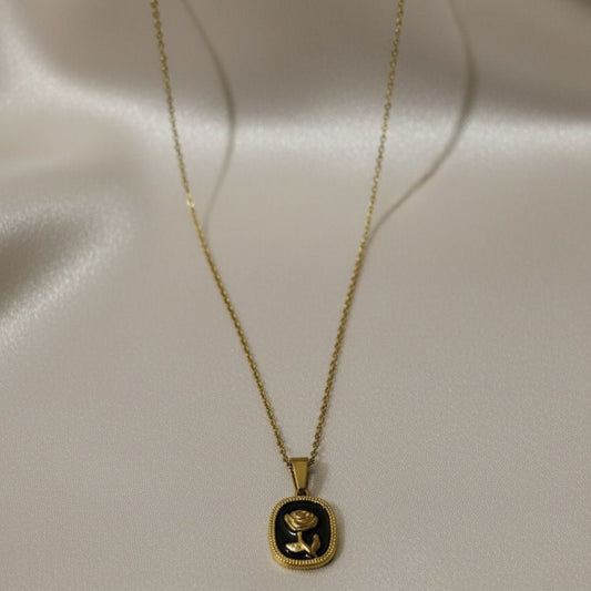 Gold necklace with a black pendant on a light gray background