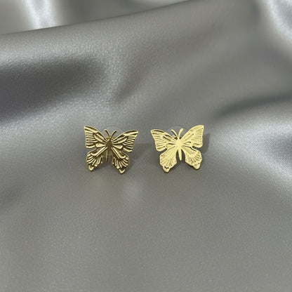 Gold butterfly earrings on a silver satin background