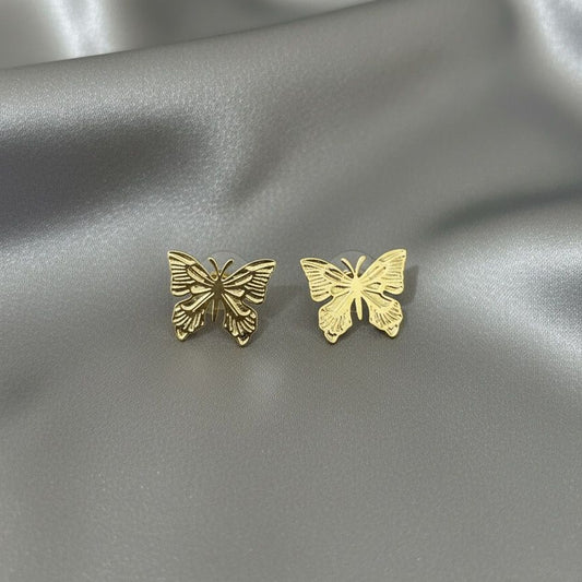 Gold butterfly earrings on a silver satin background